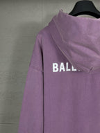 Purple long hoodie with adjustable hood and partial back BALENCIAGA logo lettering.