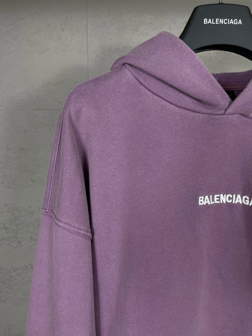 Purple long hoodie with sloped shoulder seams and partial side BALENCIAGA logo print.