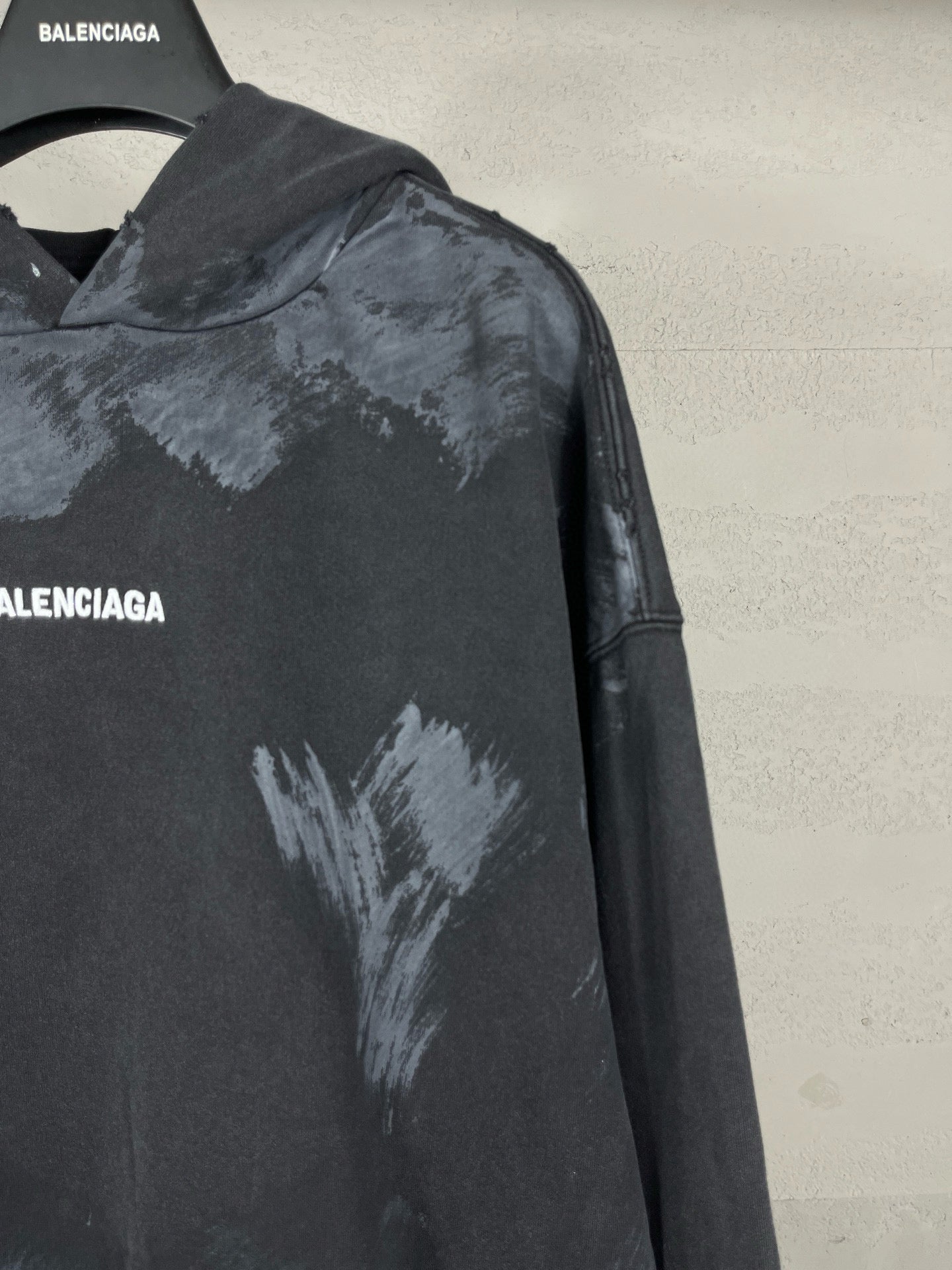 Balenciaga hoodie shoulder and sleeve detail with distressed print on dark fabric