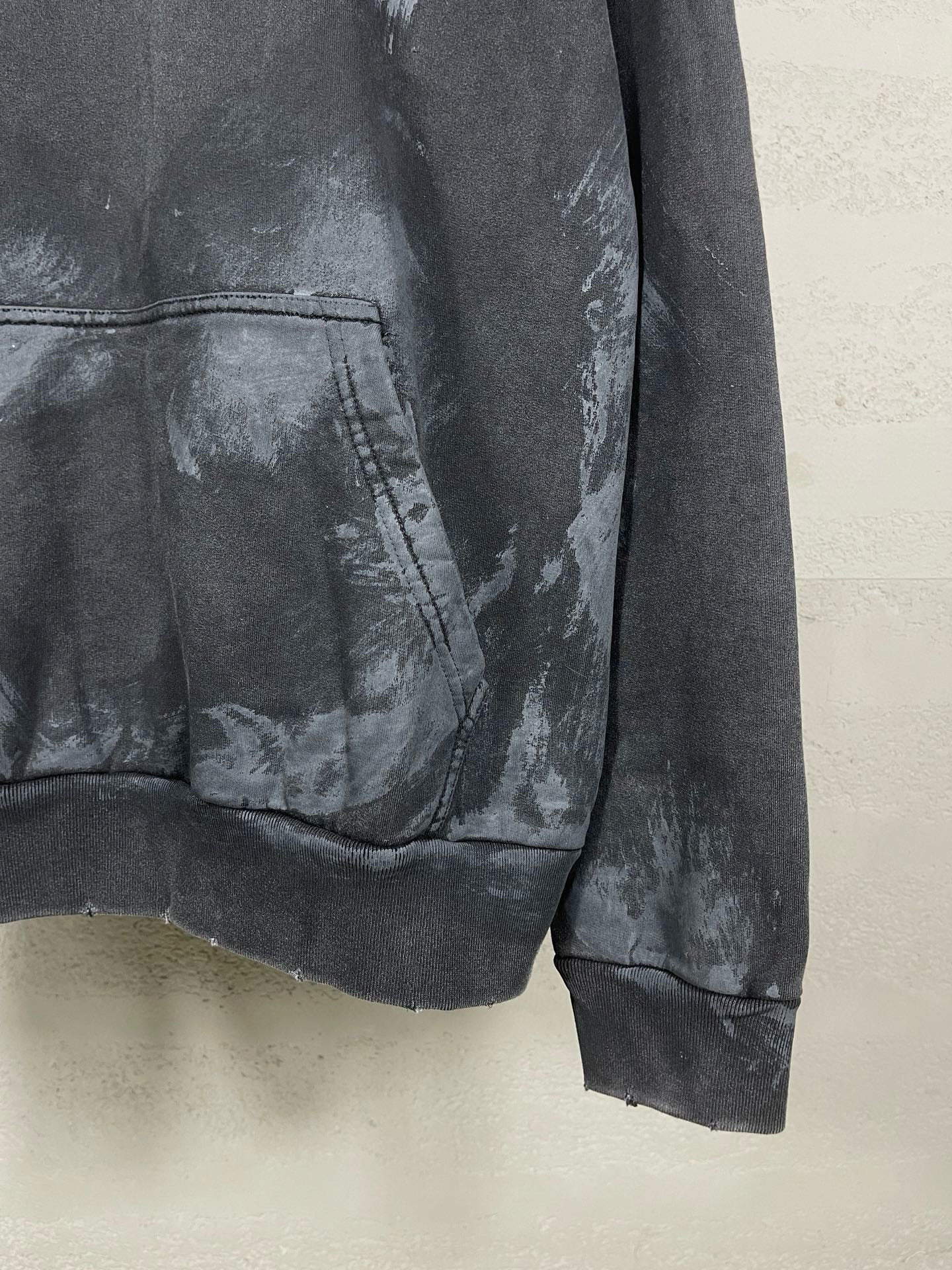 Balenciaga hoodie hem and kangaroo pocket detail with distressed print on dark fabric