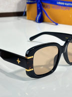 Louis Vuitton sunglasses close-up with black frame, beige lenses, and gold logo
