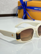 Louis Vuitton white sunglasses close-up with brown lenses and gold star ornament
