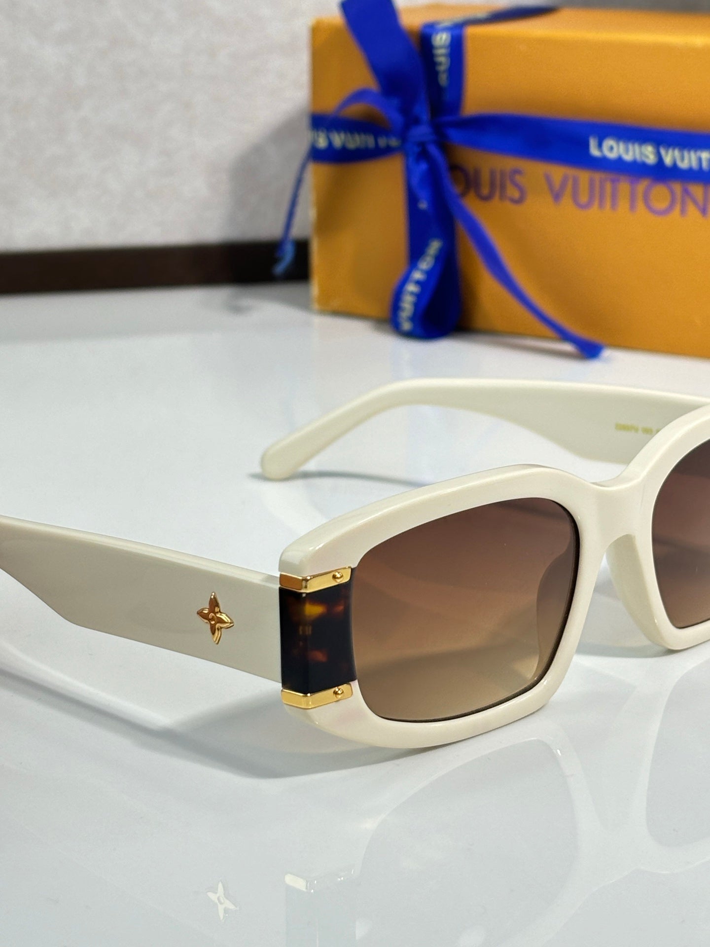 Louis Vuitton white sunglasses close-up with brown lenses and gold star ornament