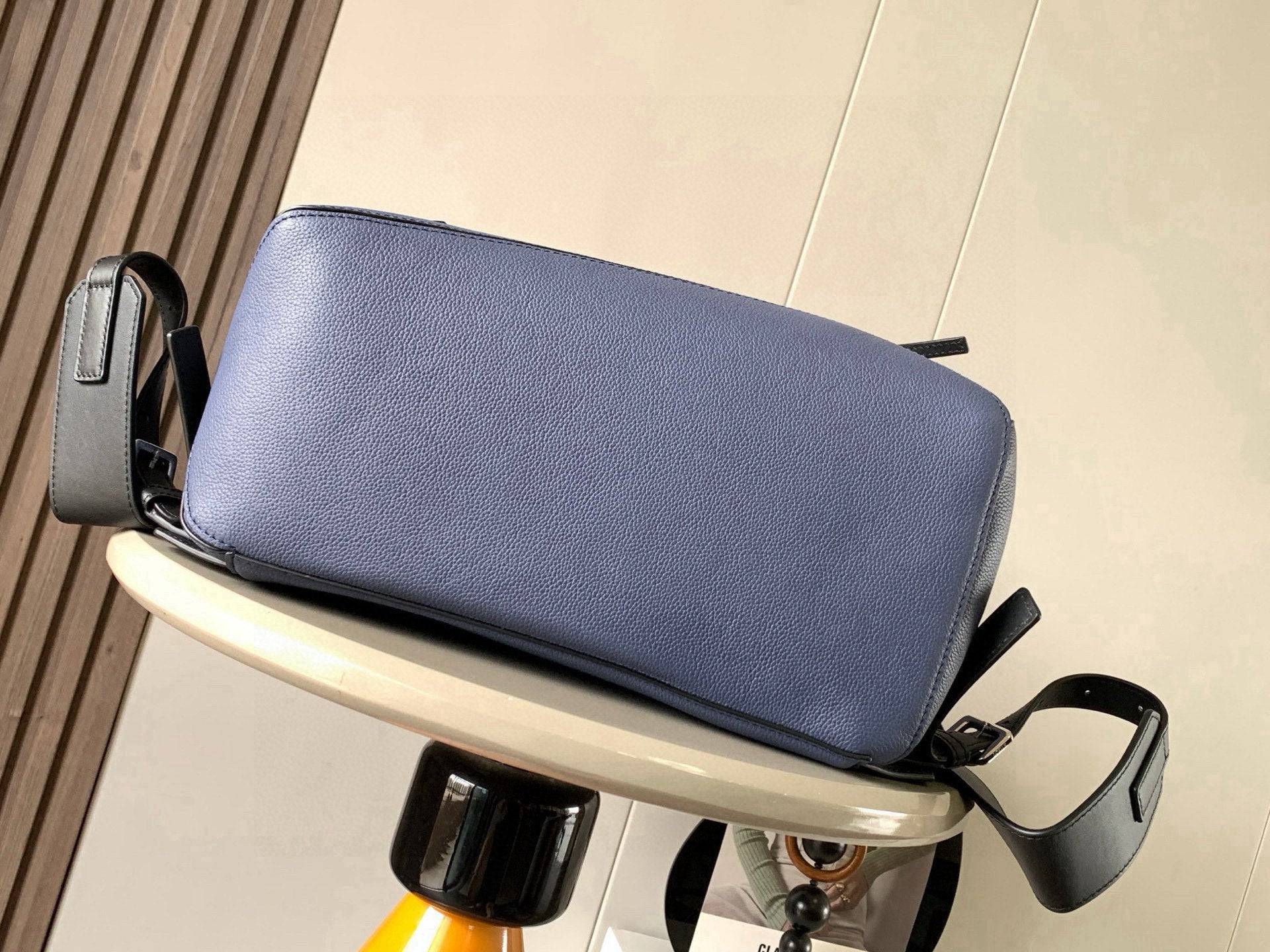 Blue leather clutch-style bag with top zipper and black shoulder strap