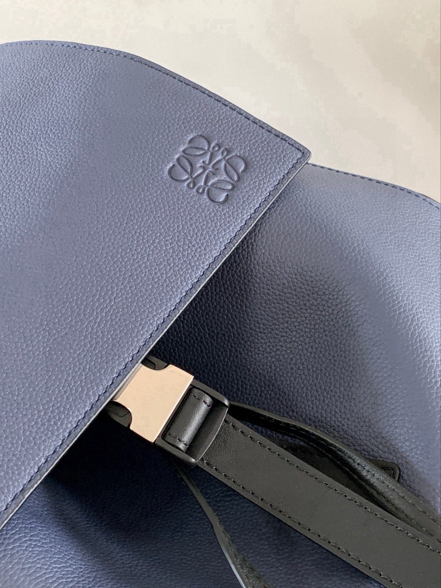 Loewe logo emboss on blue leather flap with metal clasp and strap