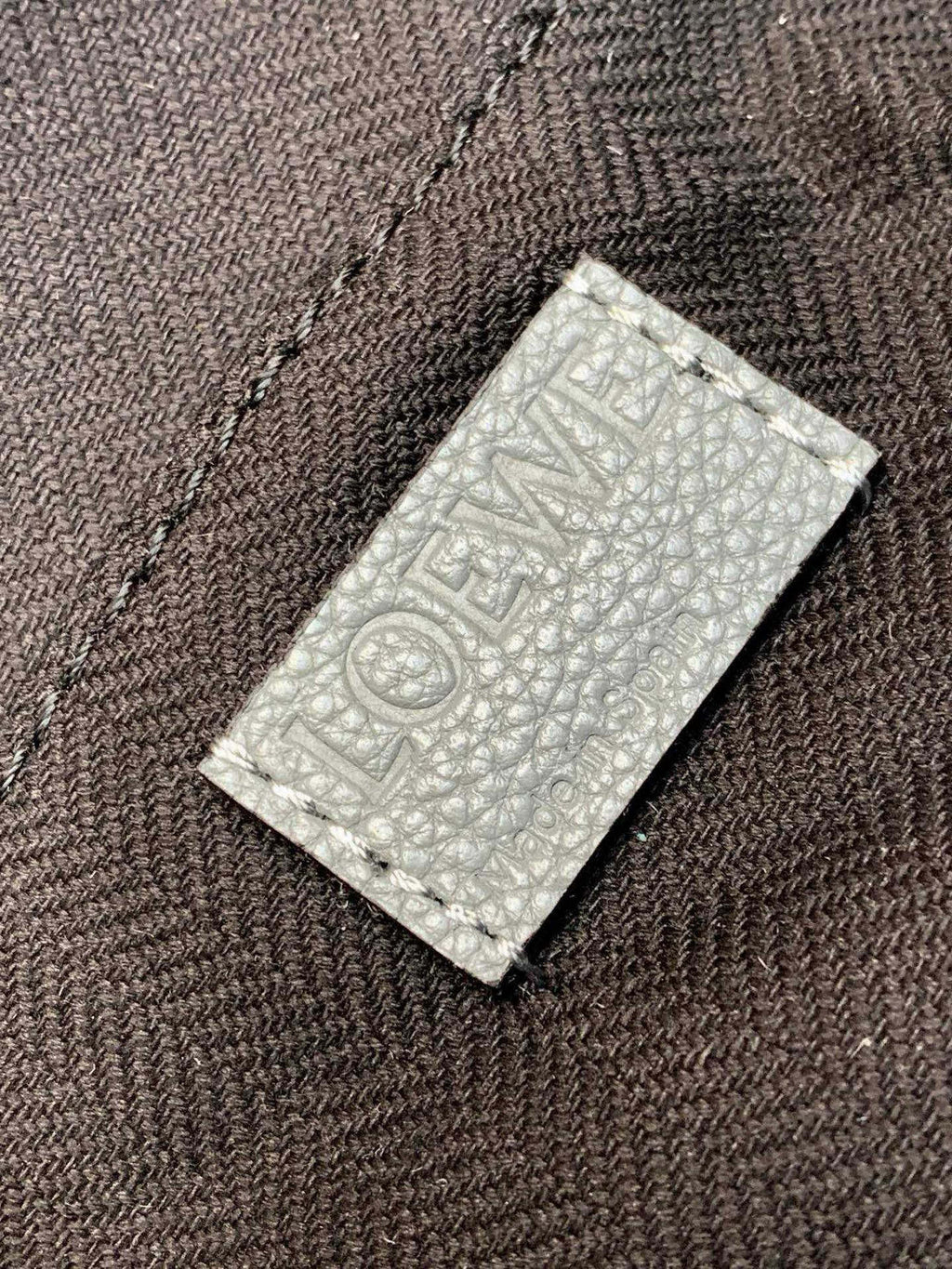 Loewe embossed leather label on light blue material backing