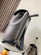 Light gray leather backpack with contrast trim, drawstring cord, and adjustable straps
