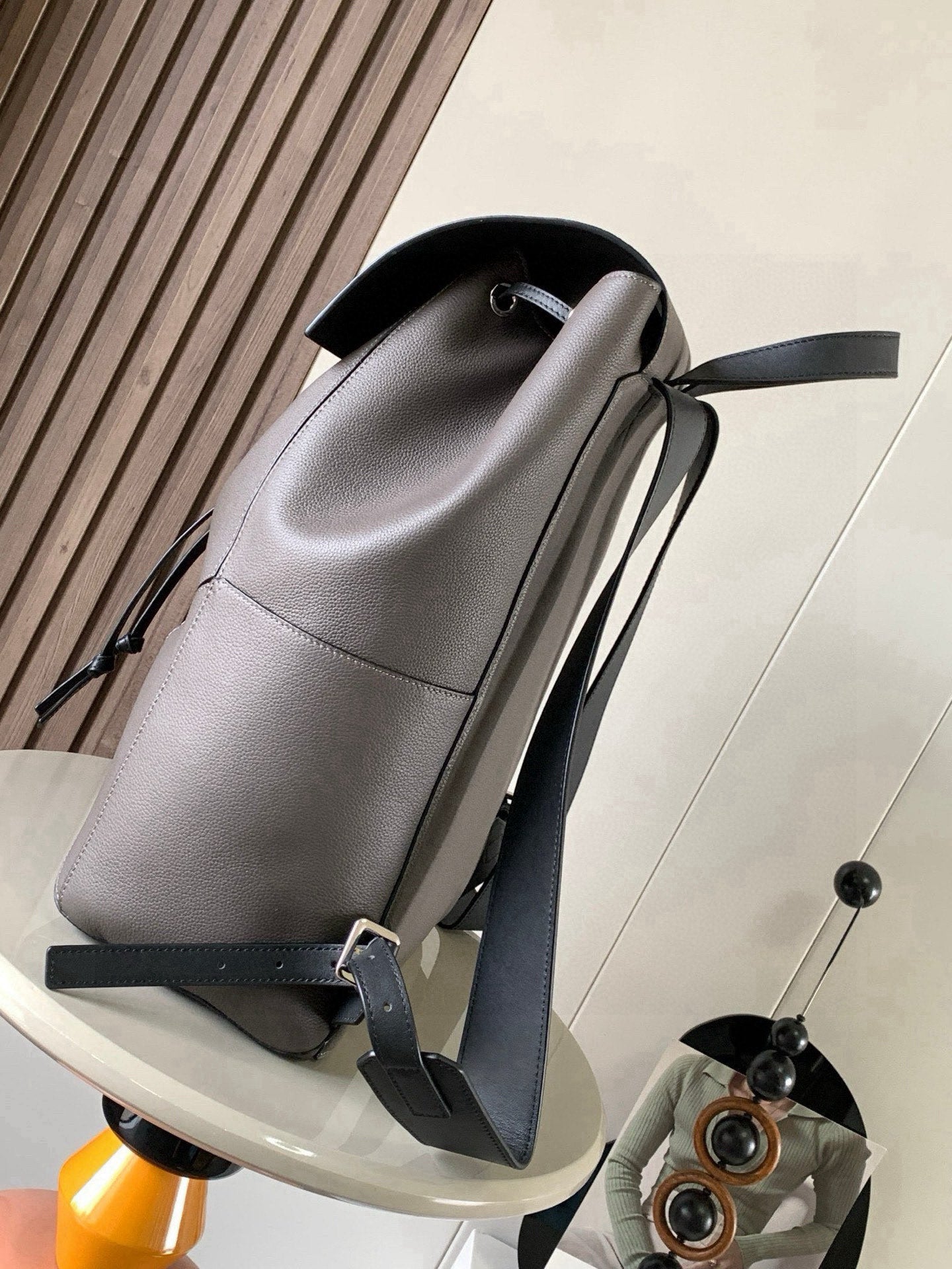 Light gray leather backpack with contrast trim, drawstring cord, and adjustable straps