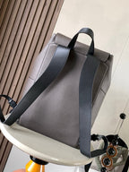 Light gray leather flap backpack with wide front panel and adjustable crossbody strap