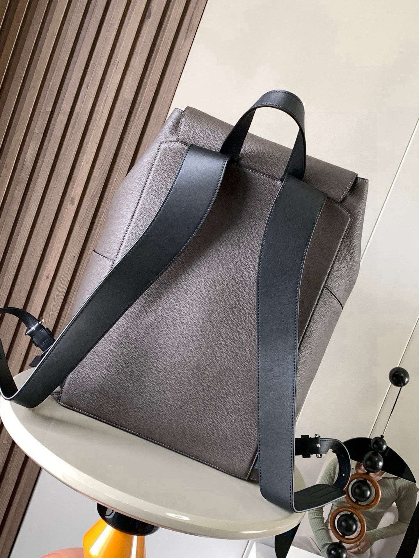 Light gray leather flap backpack with wide front panel and adjustable crossbody strap