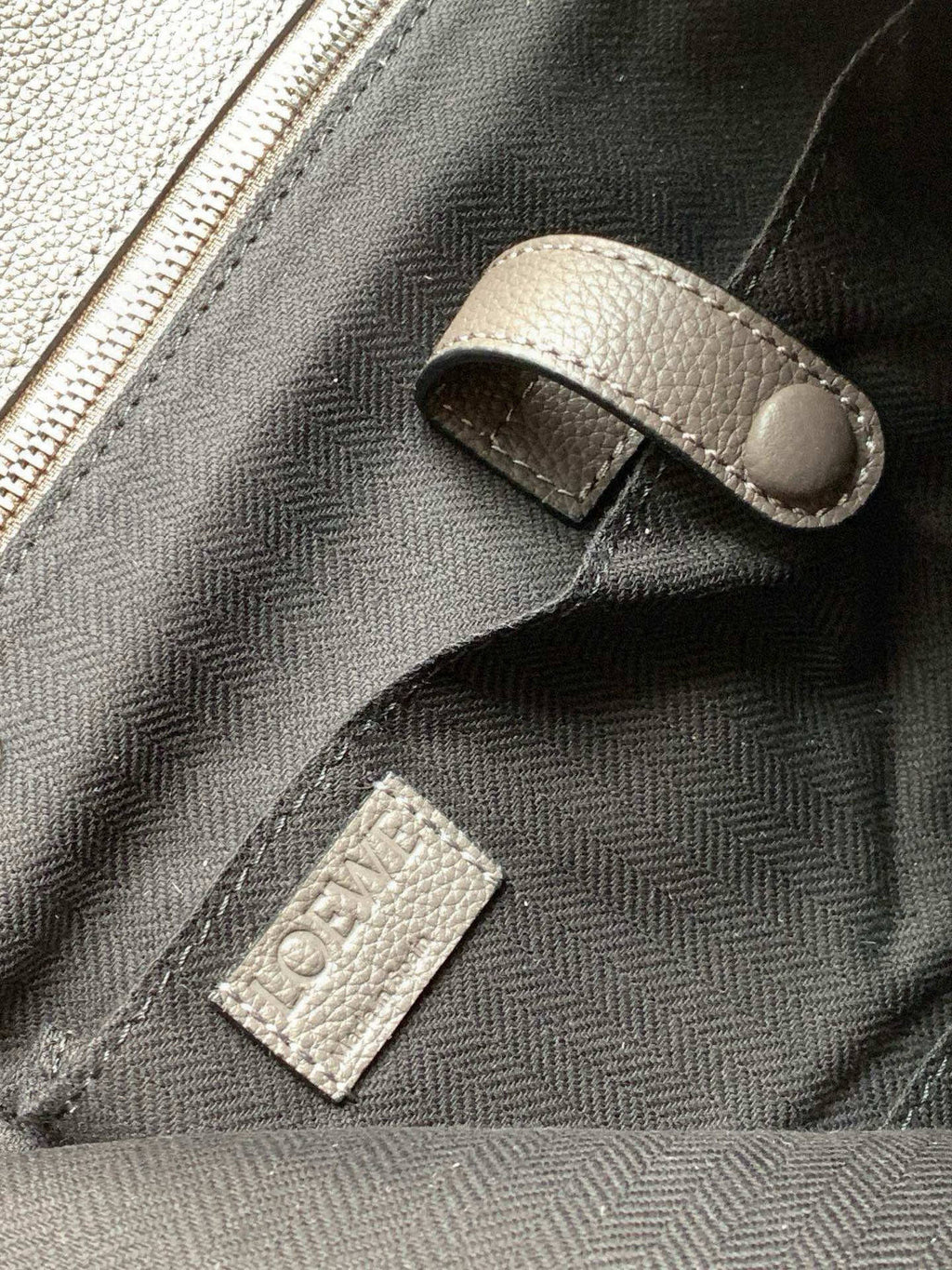 Loewe men’s bag close-up, metallic gray leather with zipper pull and stitched label
