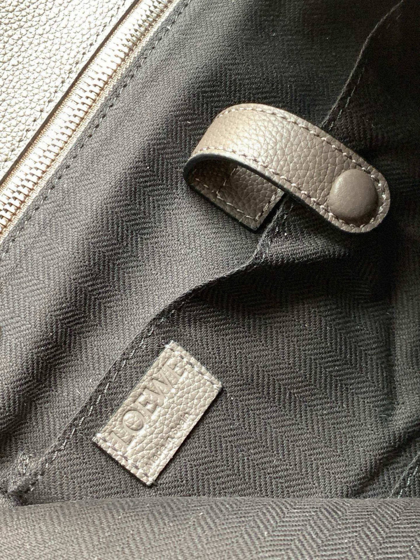 Close-up of light gray pebbled leather zipper pull and interior label patch