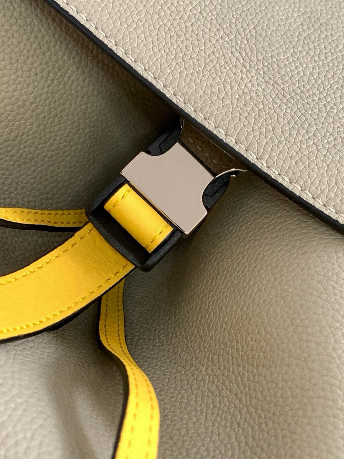 Loewe bag close-up of yellow leather strap with black buckle and light leather edge