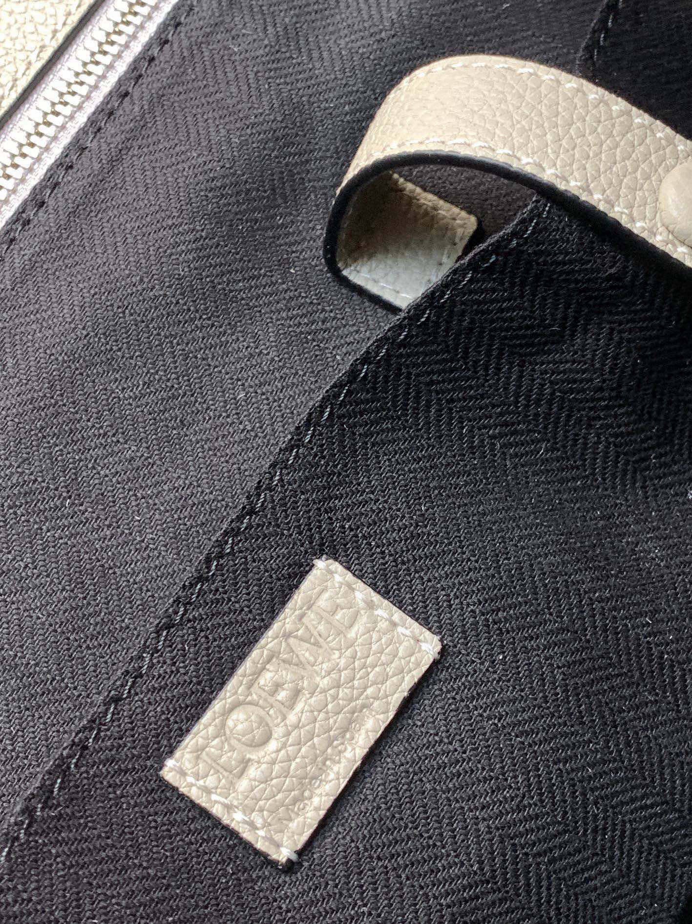 Loewe men's bag fabric tag on dark woven panel with off-white leather tab