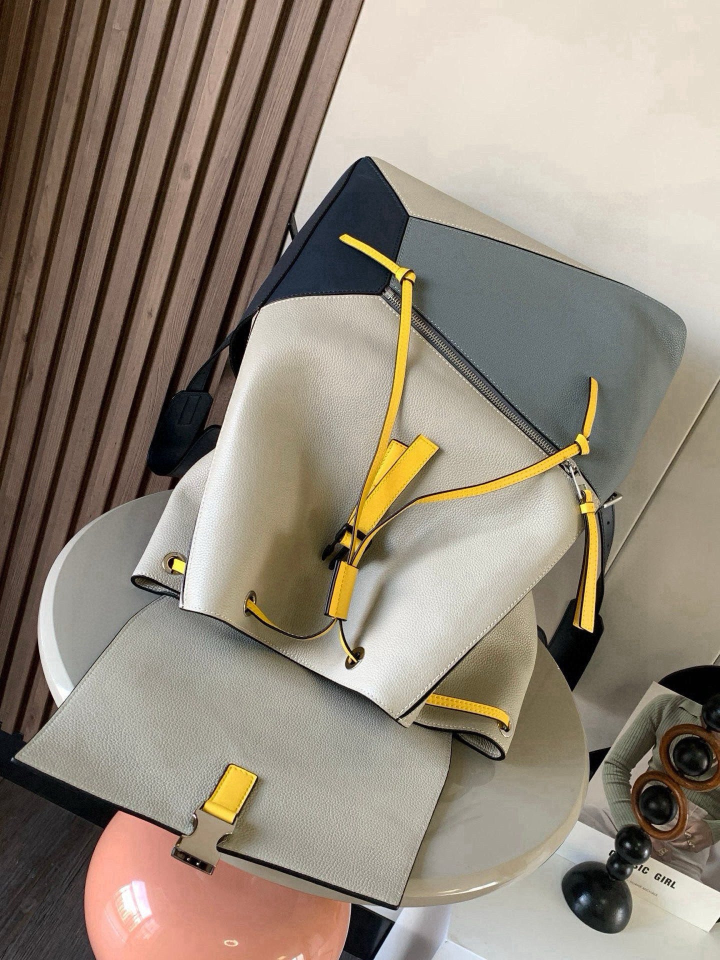 Loewe men's bag with cream body, blue trim and yellow cords, folded strap detail