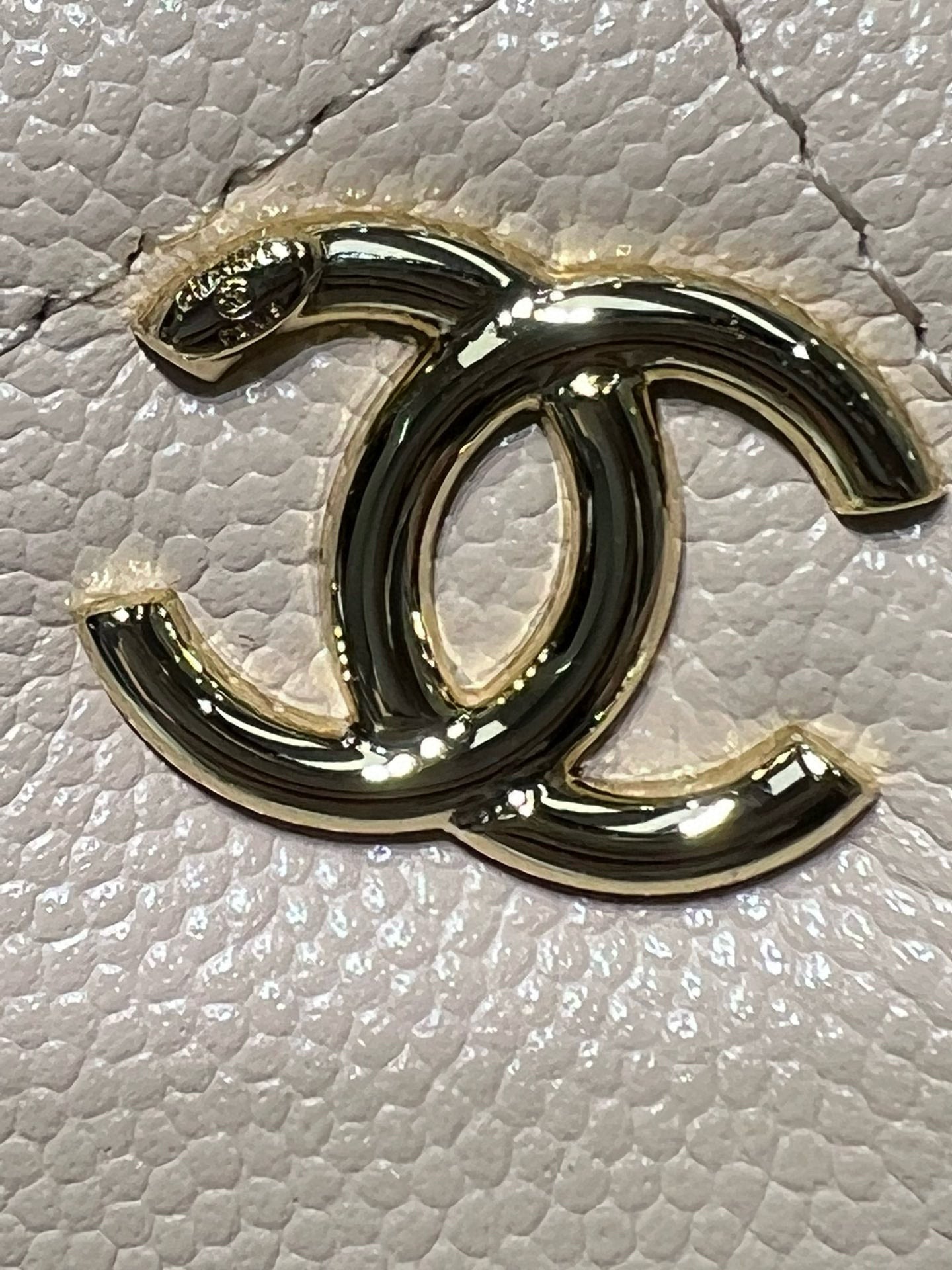 Gold-tone Chanel logo charm on textured light leather