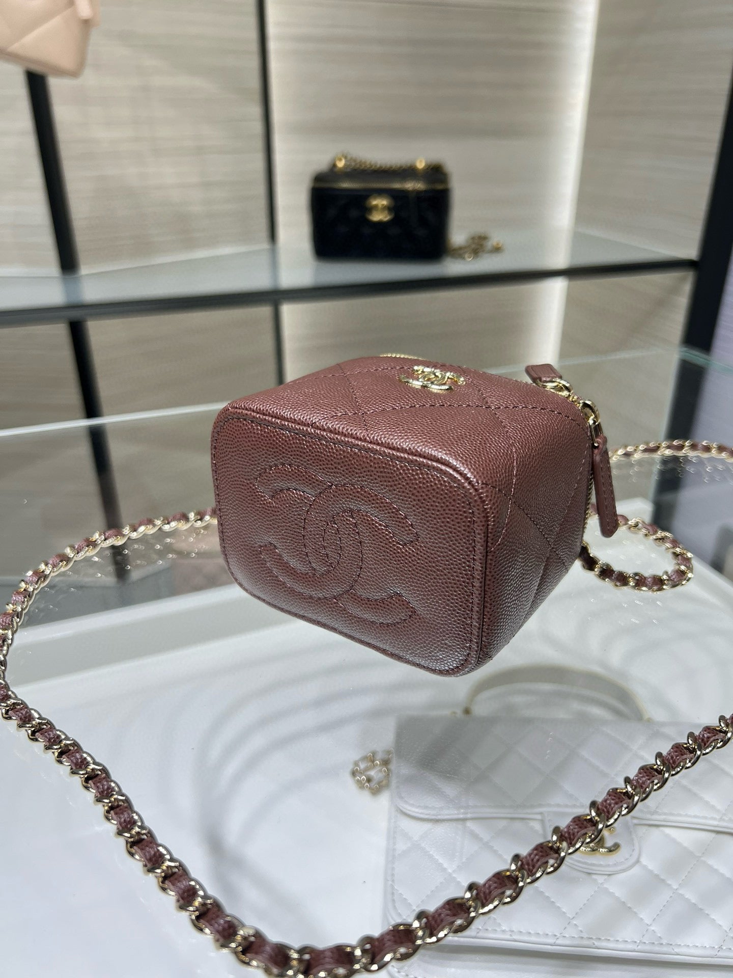 Maroon textured mini handbag with gold clasp and crossbody chain strap