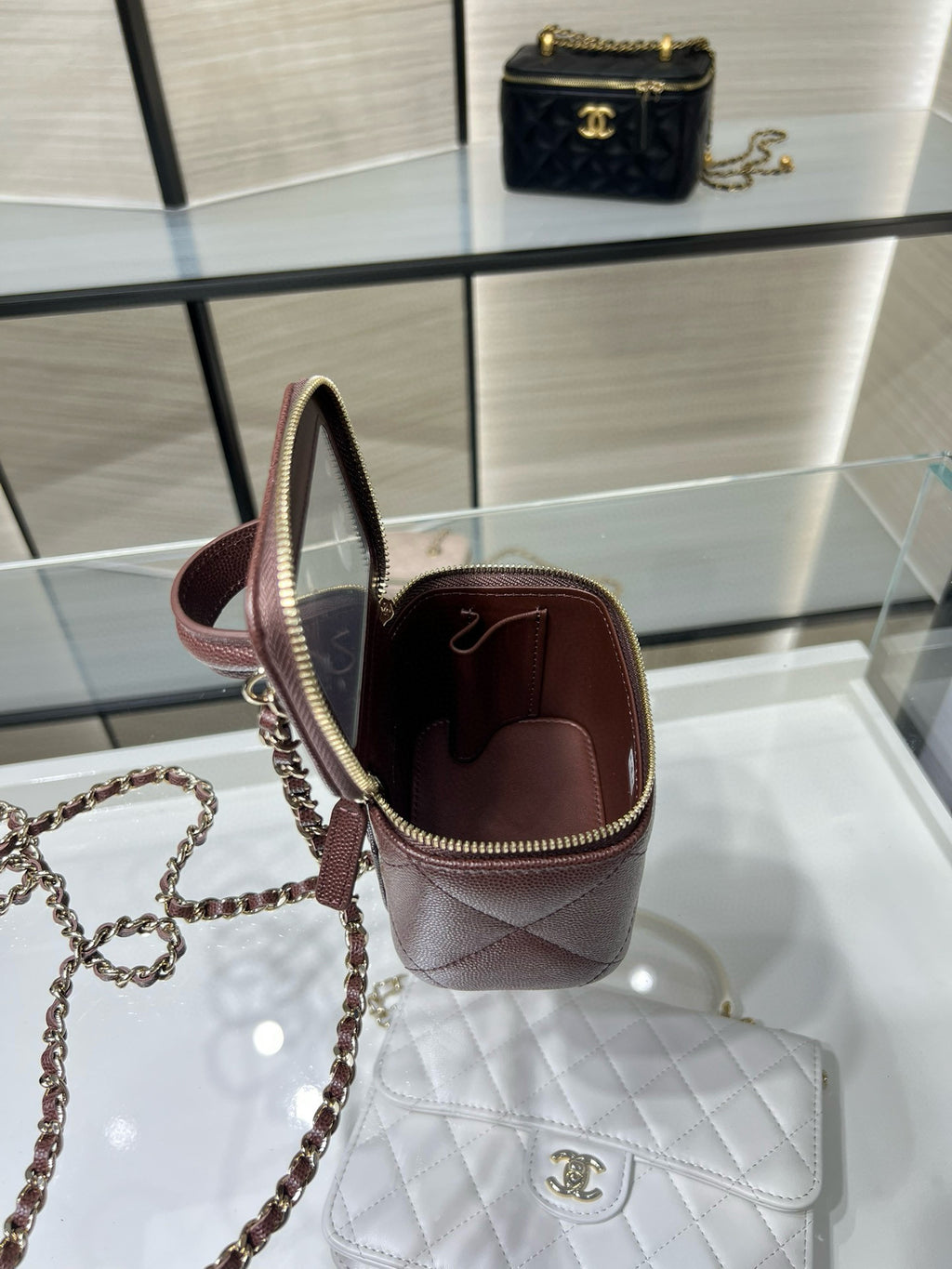 Maroon mini handbag with open top and gold zipper on display