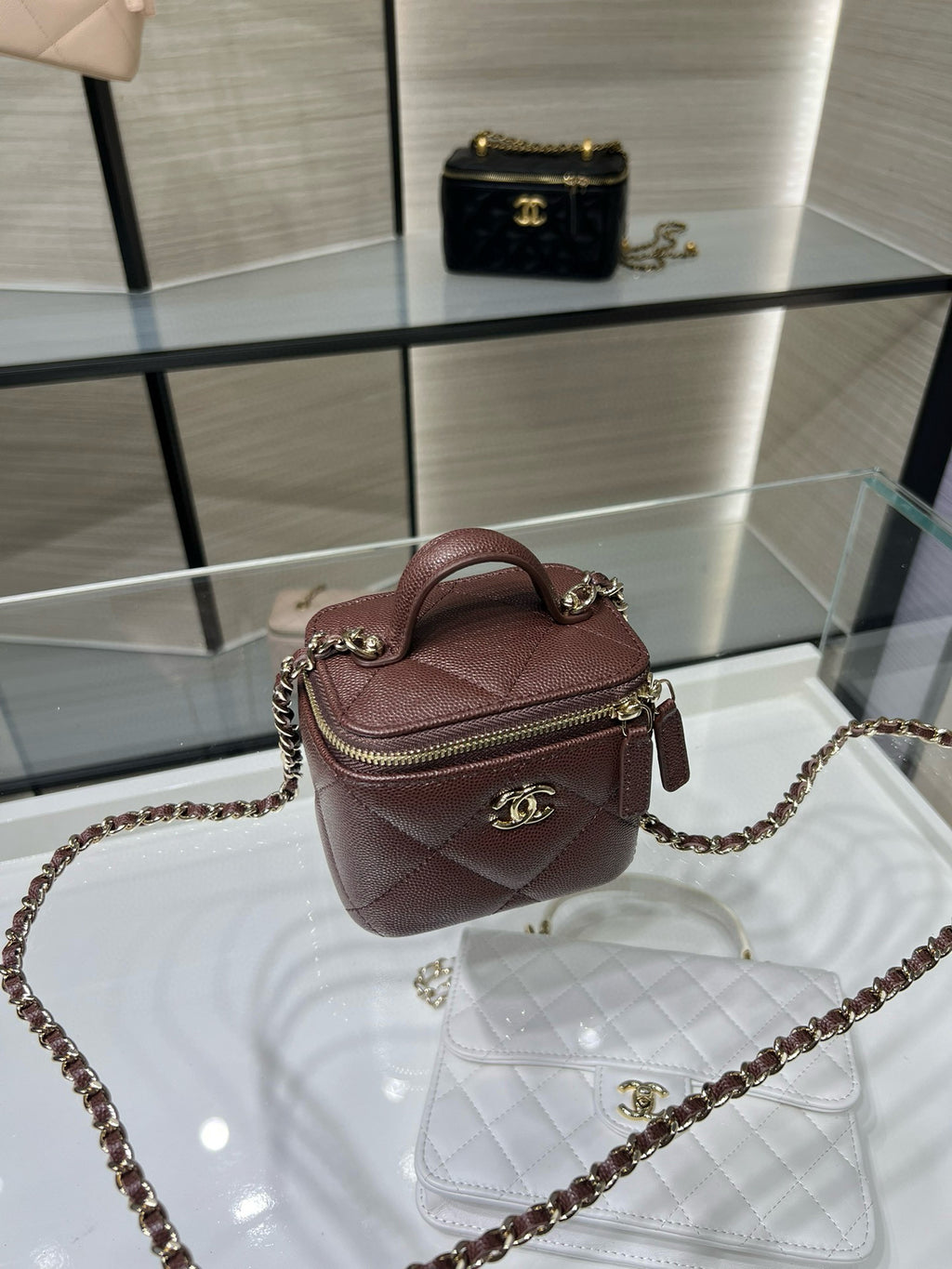 Maroon mini handbag with top handle, zip closure, and gold chain strap
