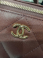 Maroon leather bag hardware with gold CC logo and zipper trim close-up