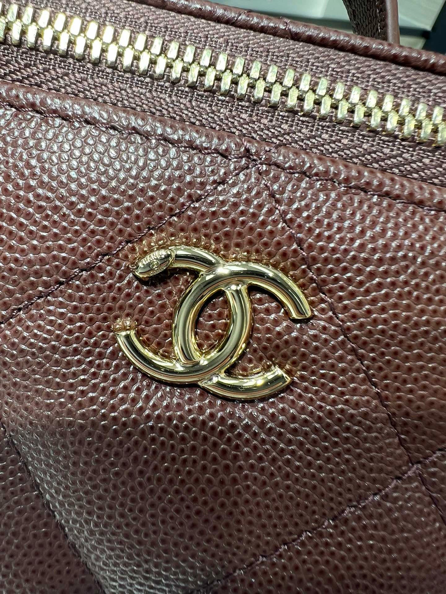 Maroon leather bag hardware with gold CC logo and zipper trim close-up