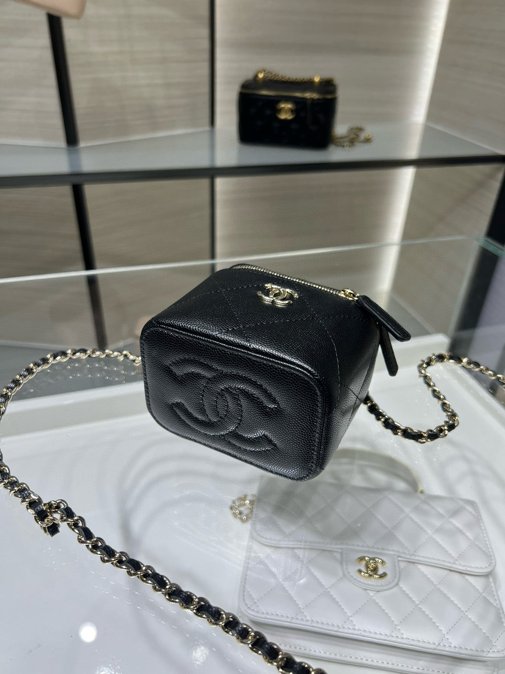 Black mini bag with gold zipper, CC emblem, and gold chain crossbody strap