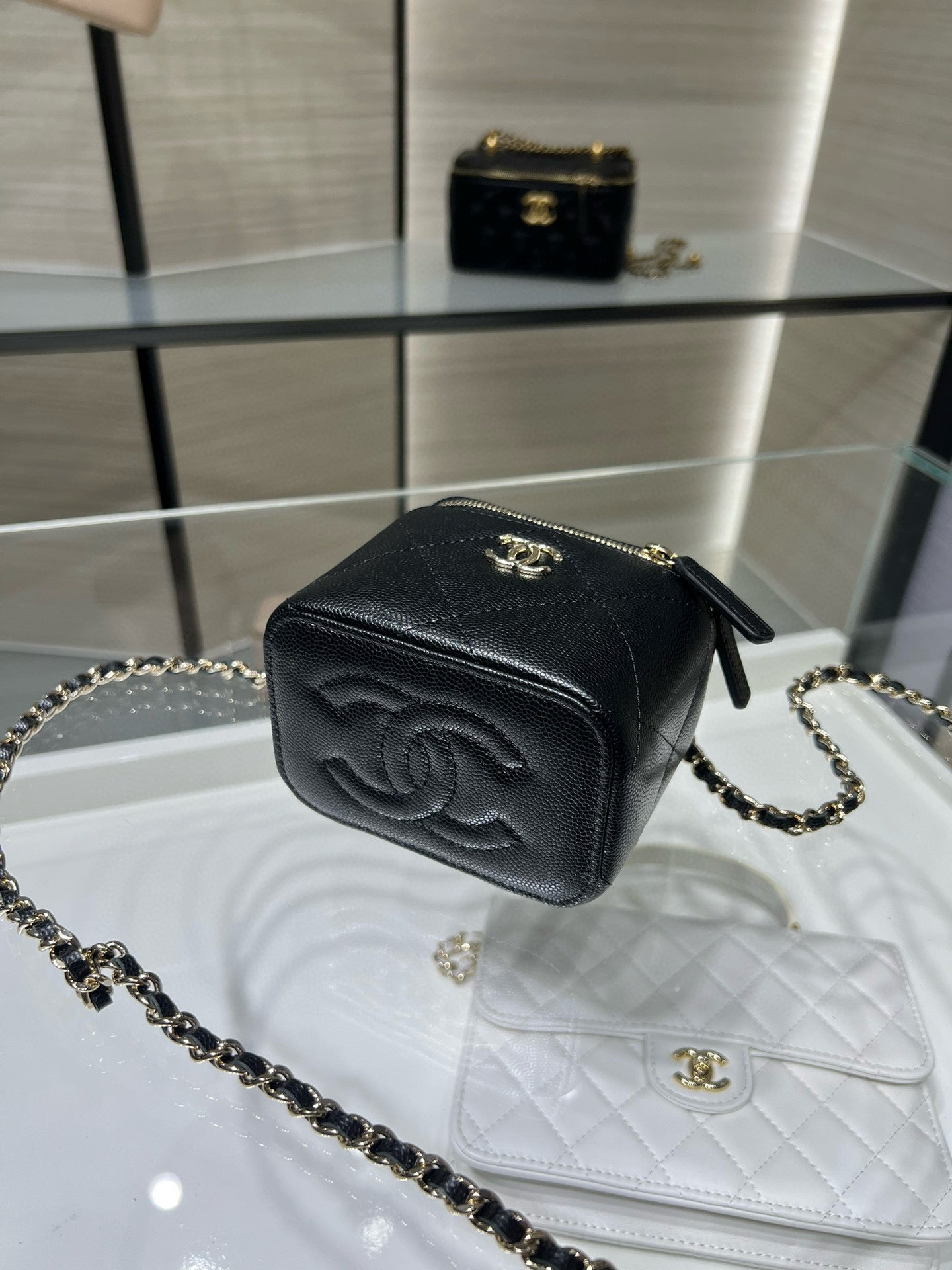 Black mini bag with gold zipper, CC emblem, and gold chain crossbody strap