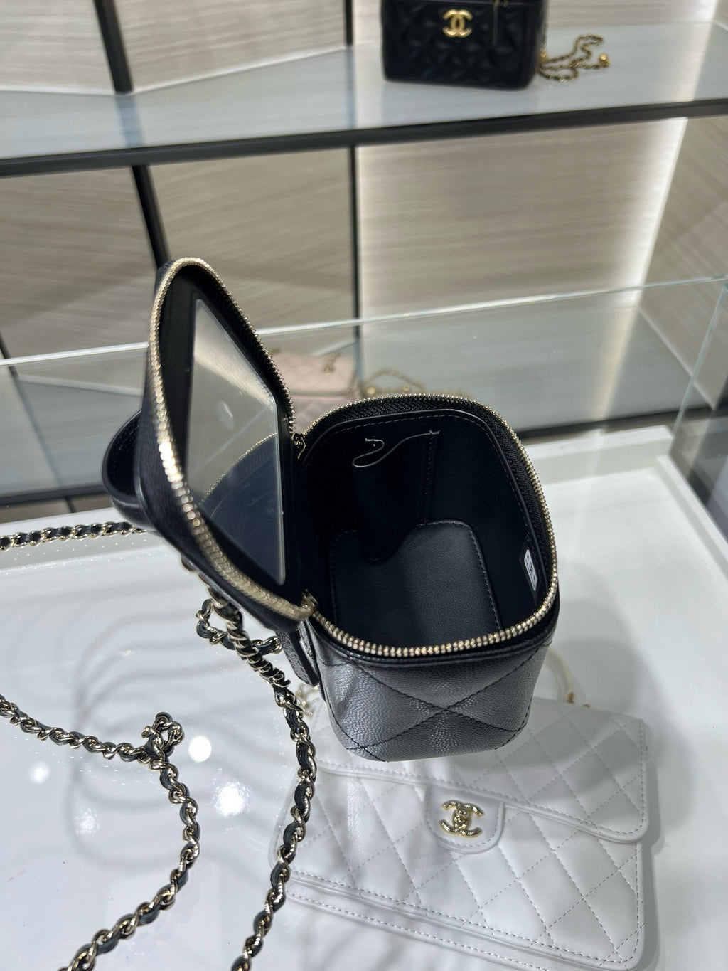 Black mini bag with gold chain strap; open top shows interior, CC emblem