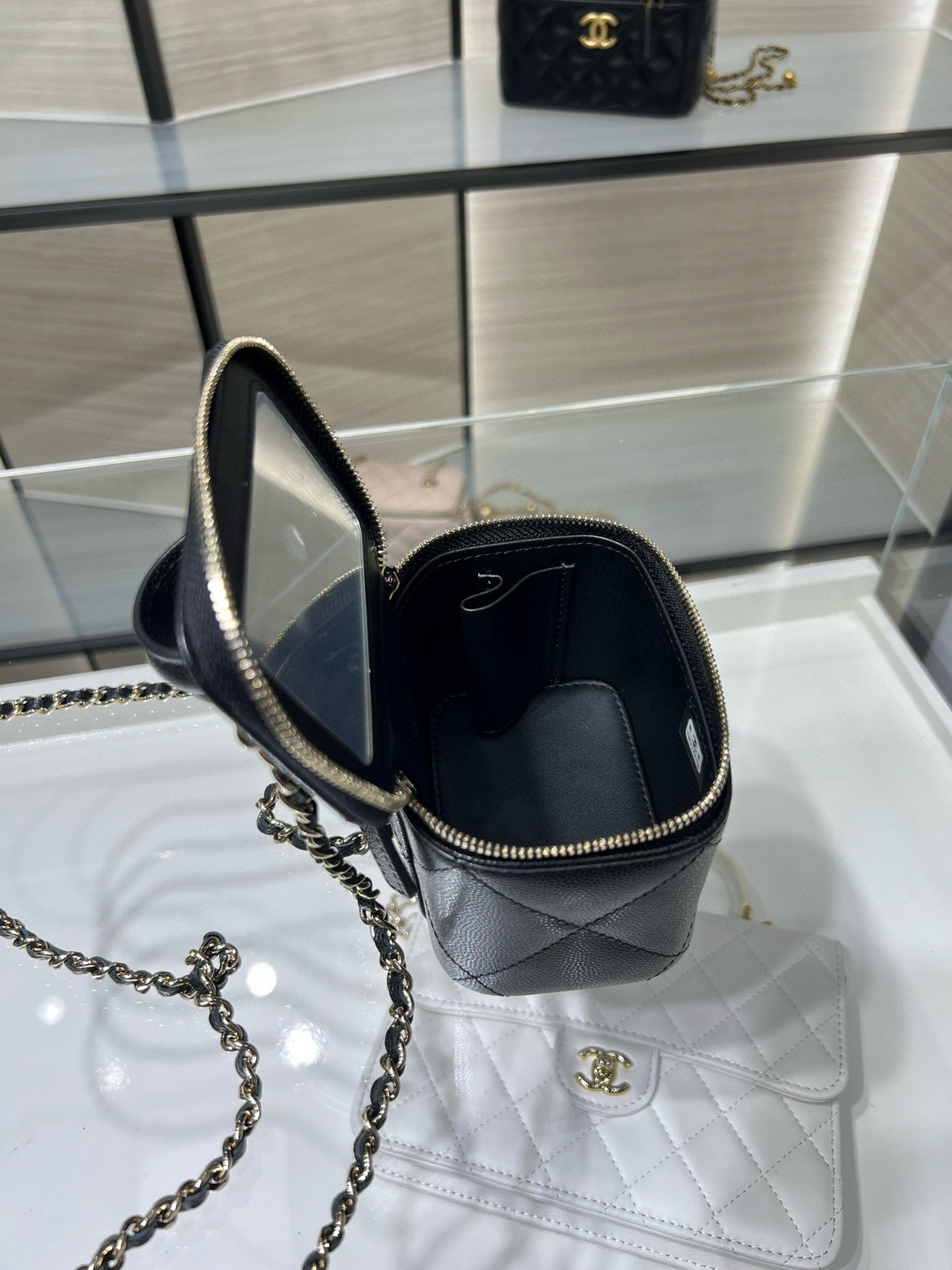 Black mini bag with gold chain strap; open top shows interior, CC emblem