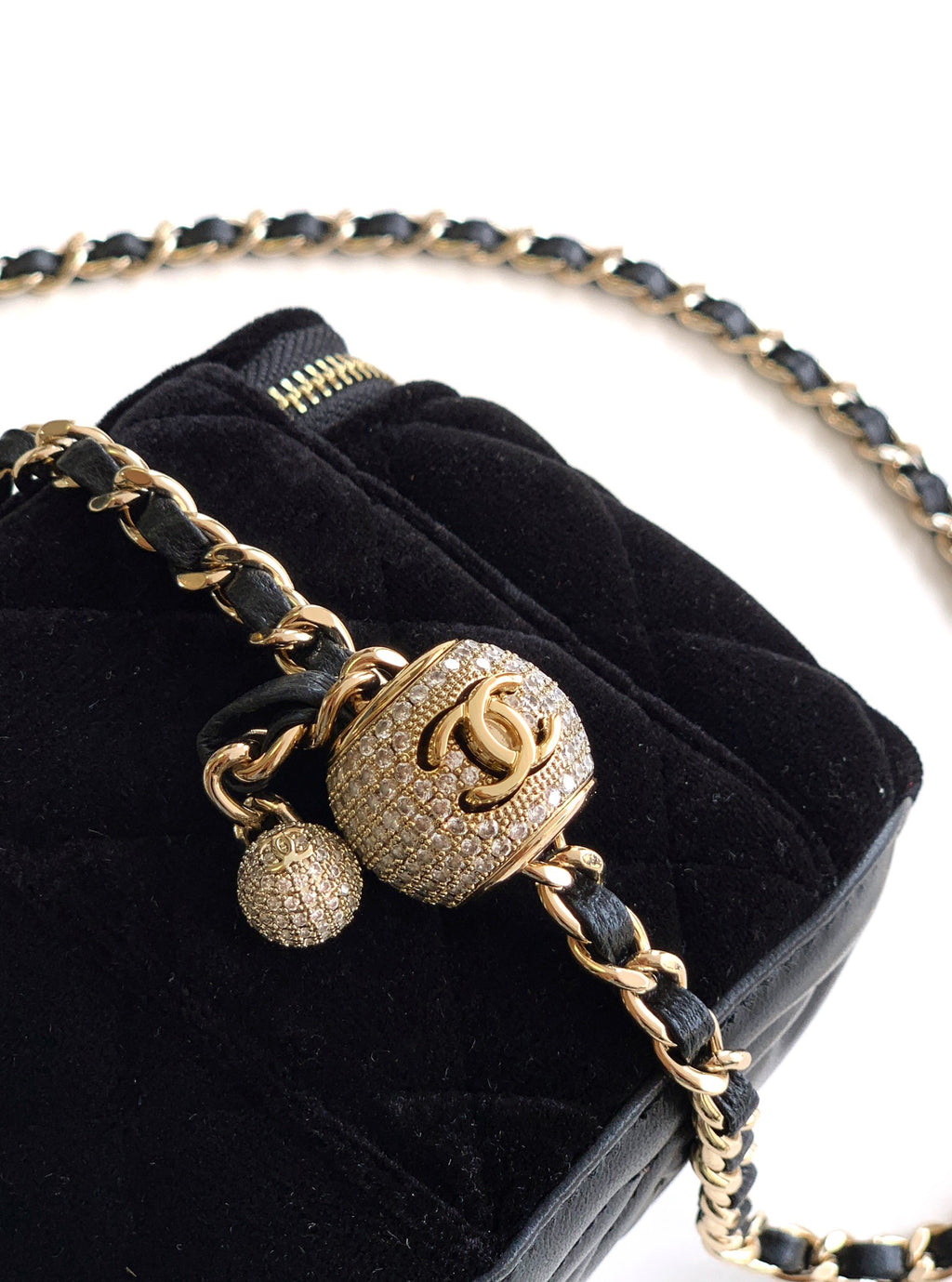 Black Chanel mini bag close-up with gold charm, chain strap, and CC emblem