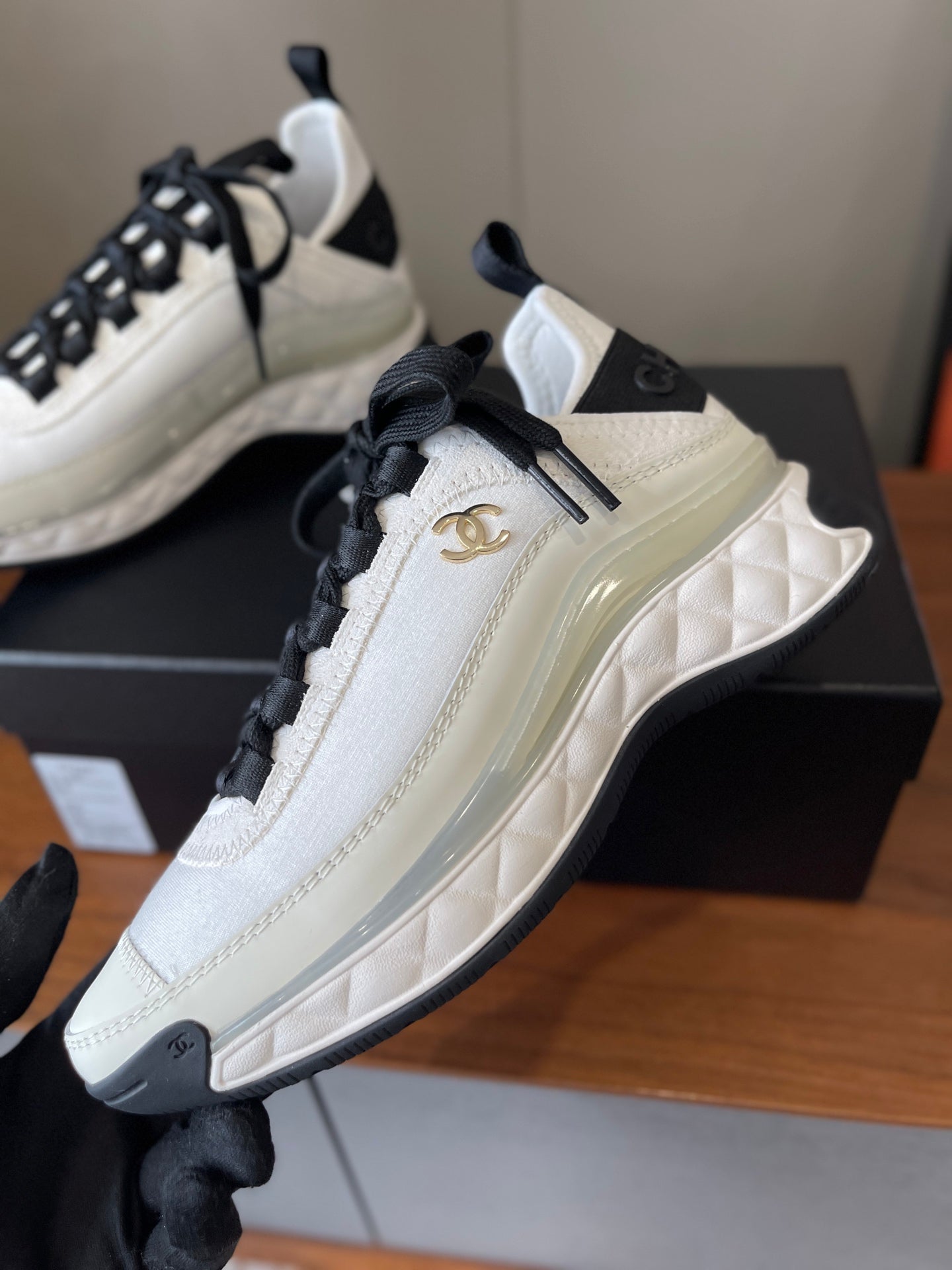 White sneaker side with black laces and gold Chanel CC emblem