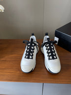 Pair of white sneakers with black lace-up fronts and navy heel tabs
