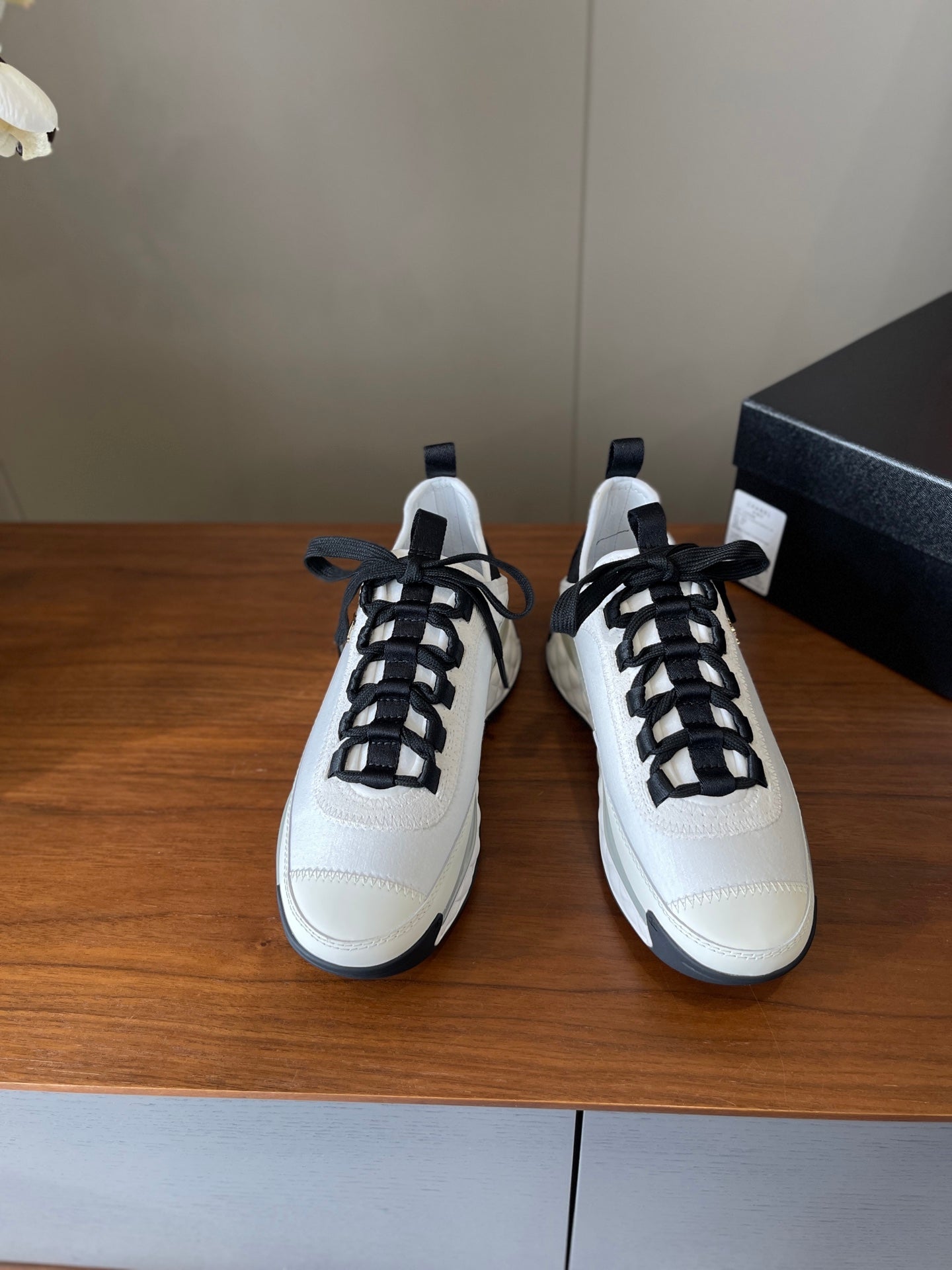 Pair of white sneakers with black lace-up fronts and navy heel tabs