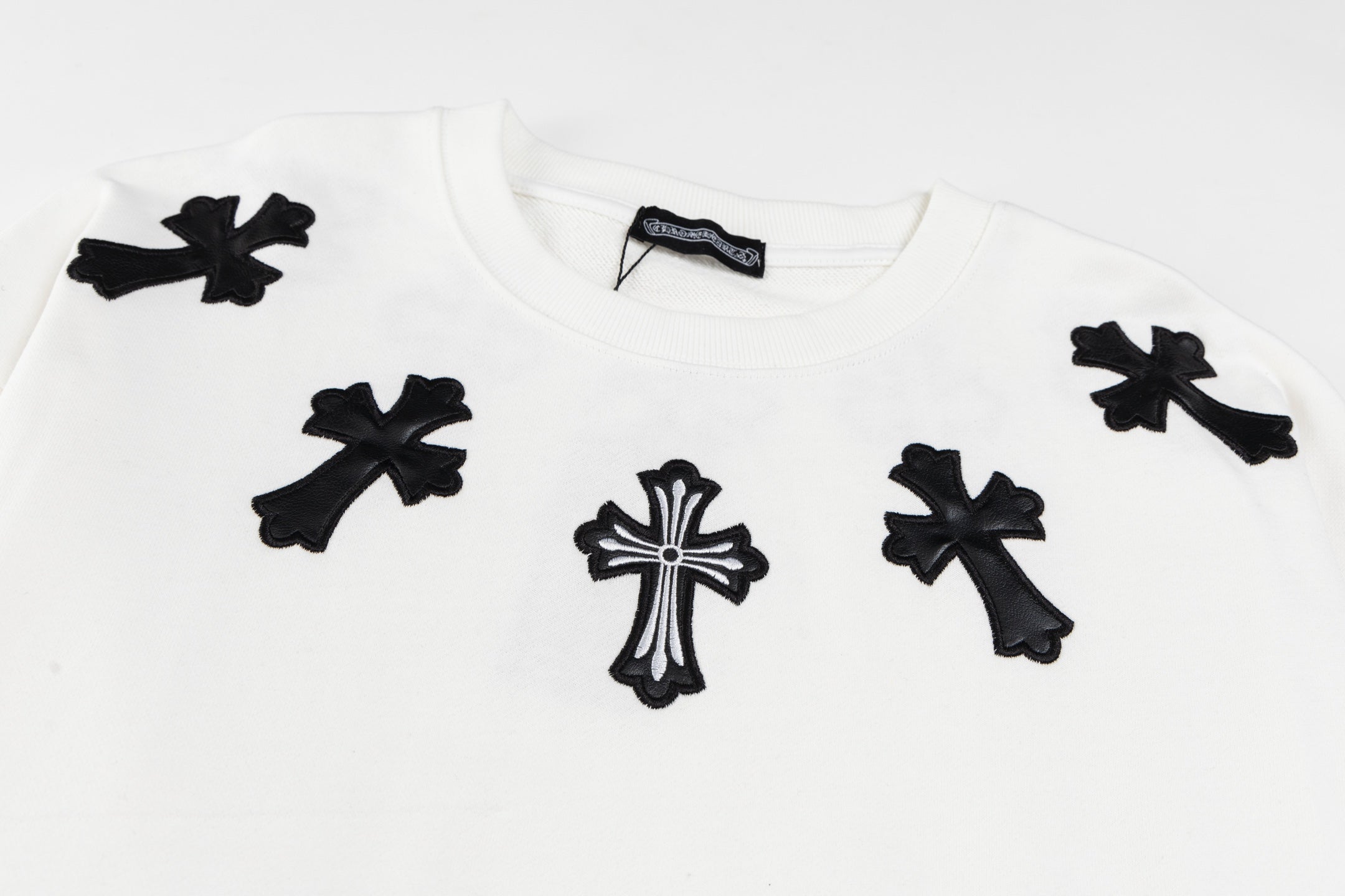 White crewneck sweatshirt with scattered black cross appliques