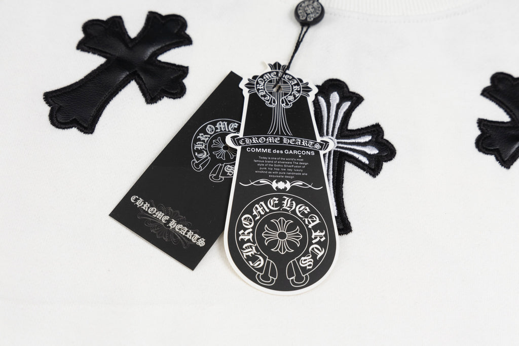 White crewneck sweatshirt detail: black cross pendant graphic and label