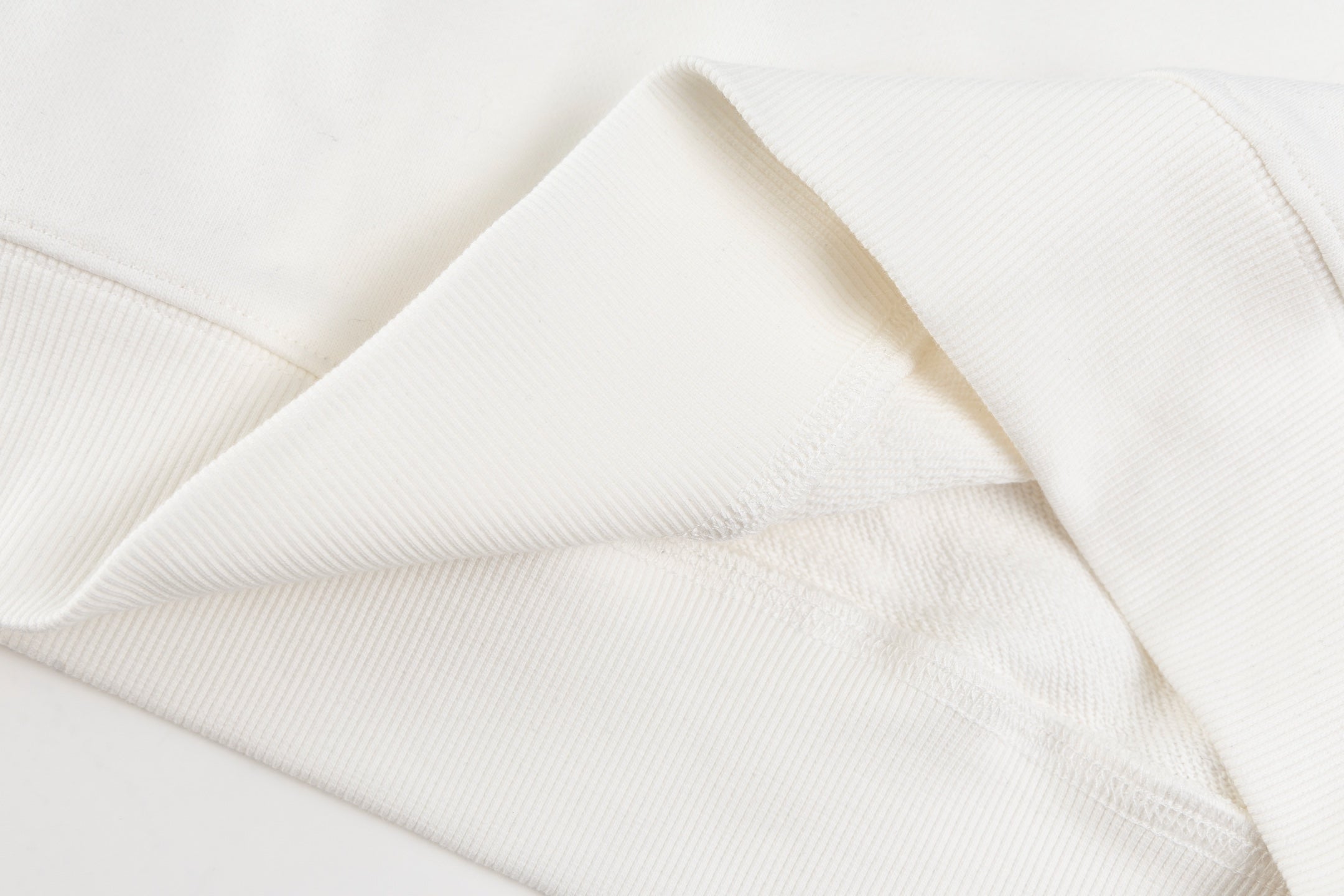 White long-sleeve garment fabric, seam and folded cuff close-up