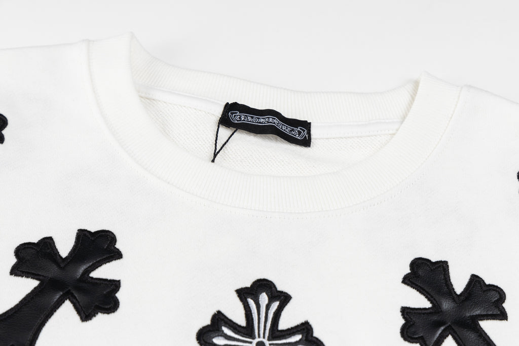 White crewneck sweatshirt neckline with black cross patch and brand label