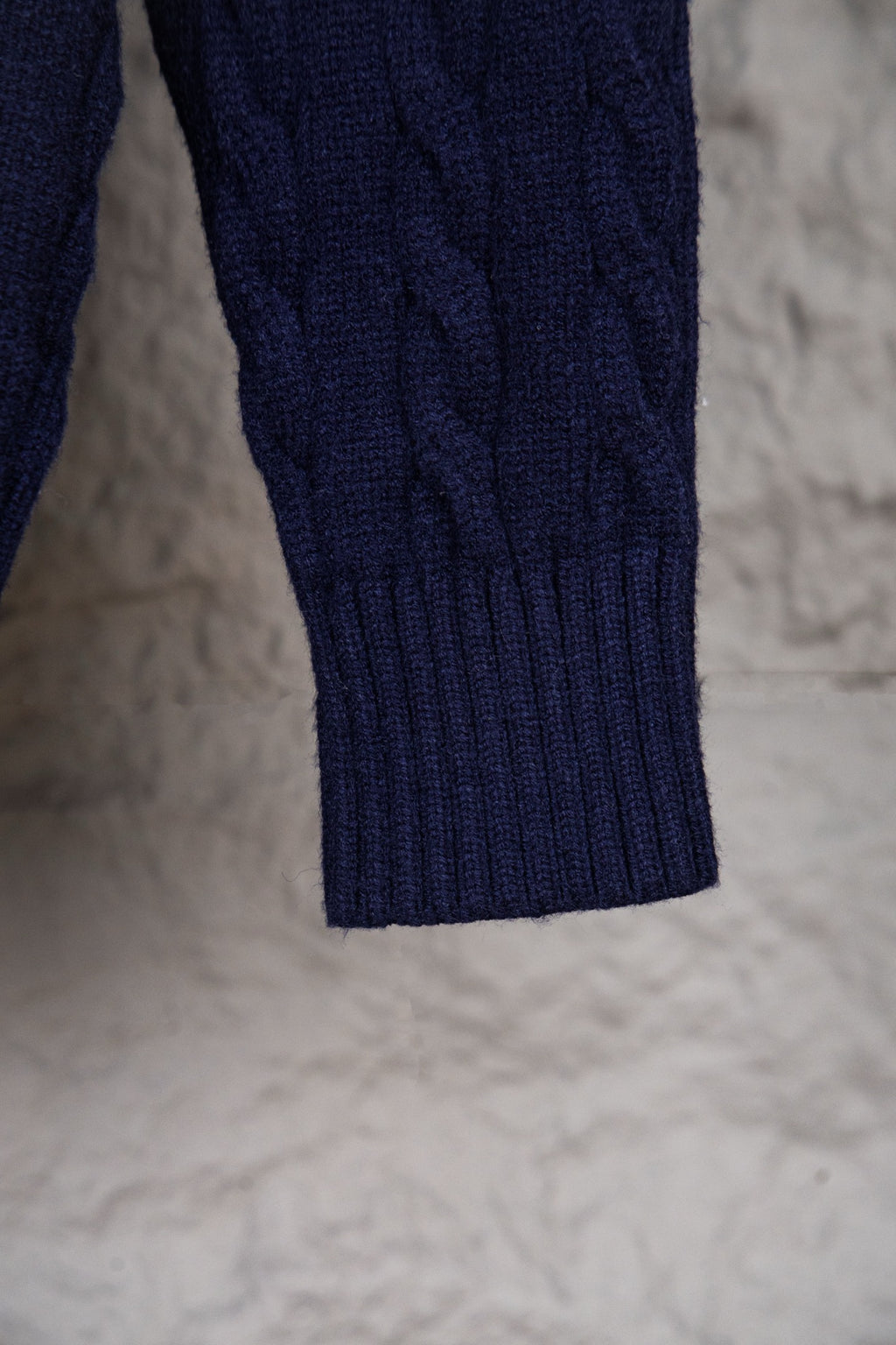 Navy knit sweater sleeve with ribbed cuff and textured cable pattern