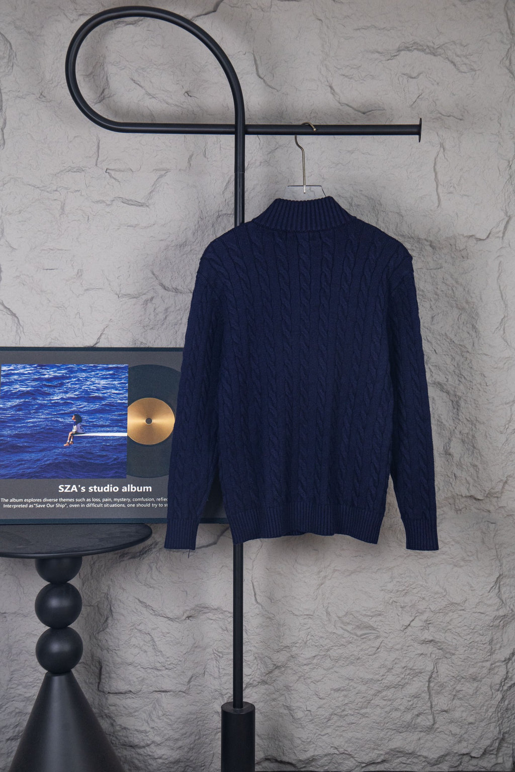 Back view of navy knit quarter-zip sweater with ribbed collar on hanger