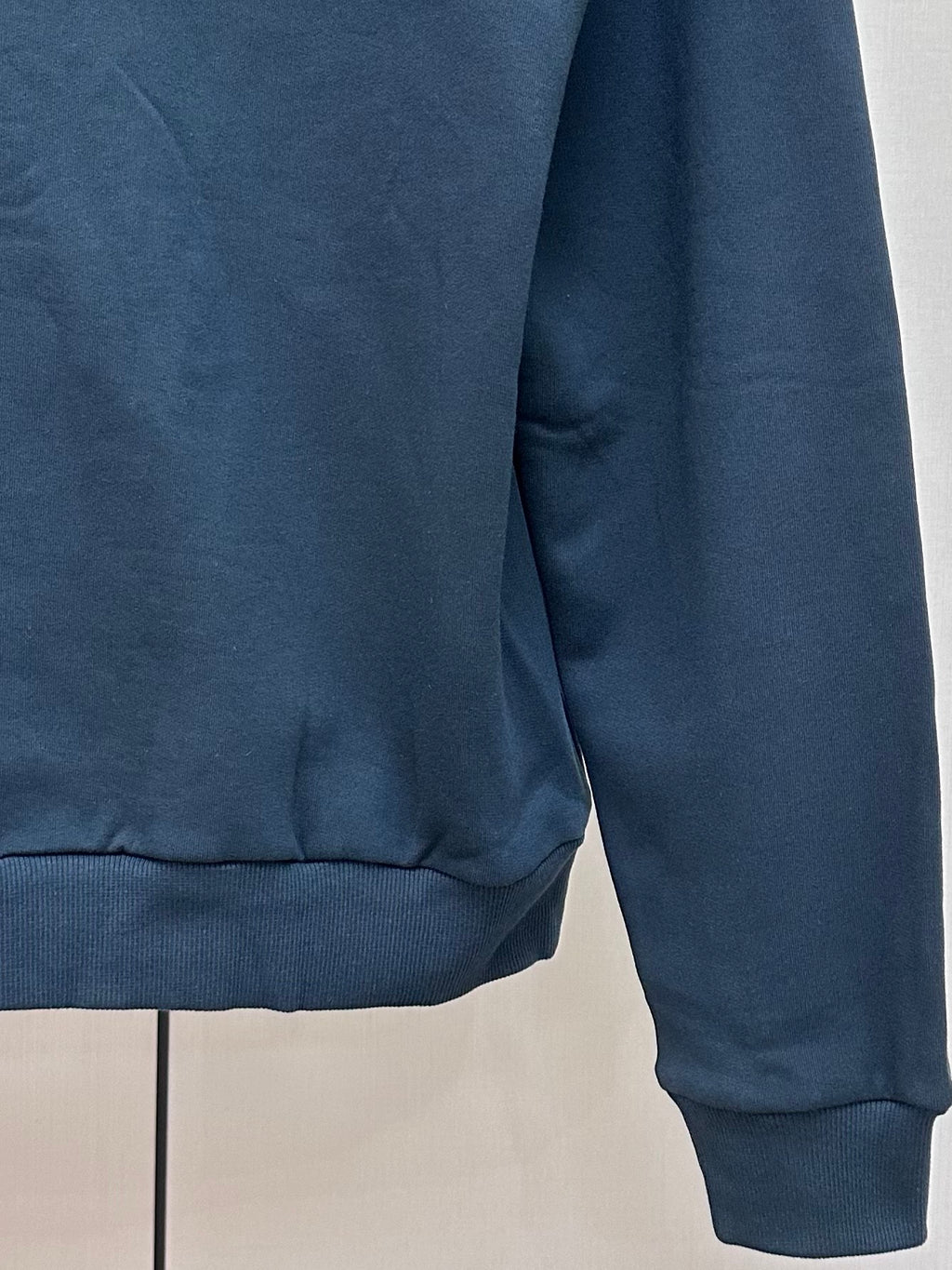 Dark blue hoodie hem and ribbed cuffs, side view
