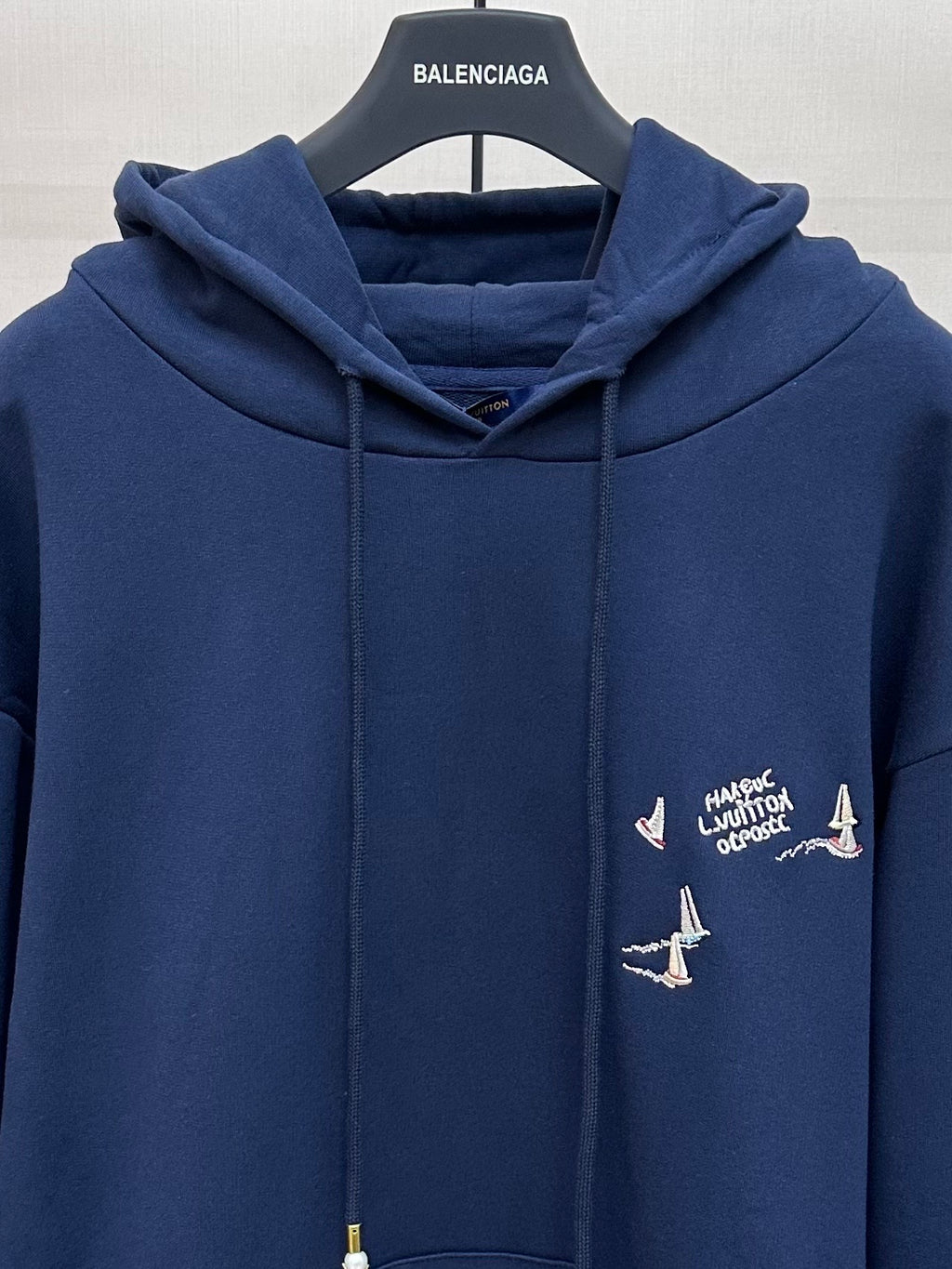 Navy hoodie with hood and drawstrings, chest graphic with sailboats