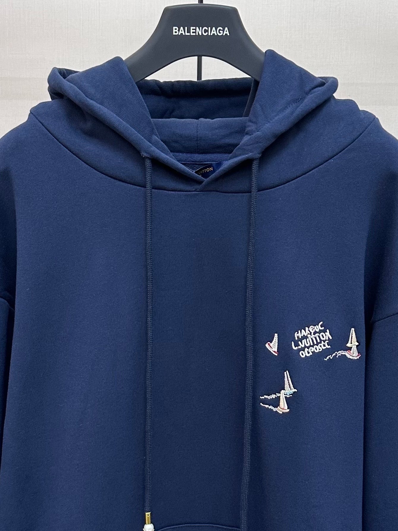 Navy hoodie with hood and drawstrings, chest graphic with sailboats