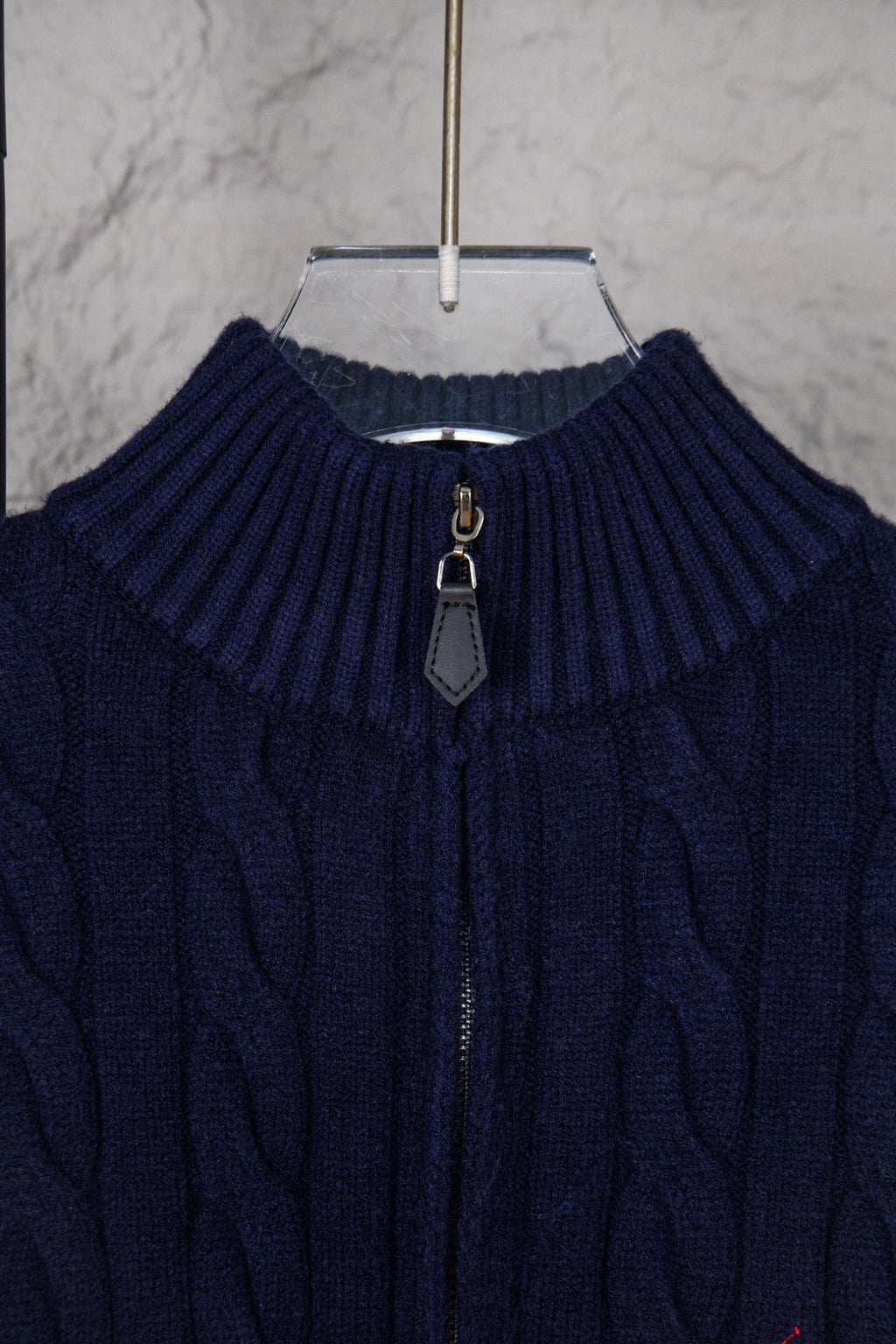 Navy cable-knit quarter-zip sweater neckline with zip pull and ribbed collar
