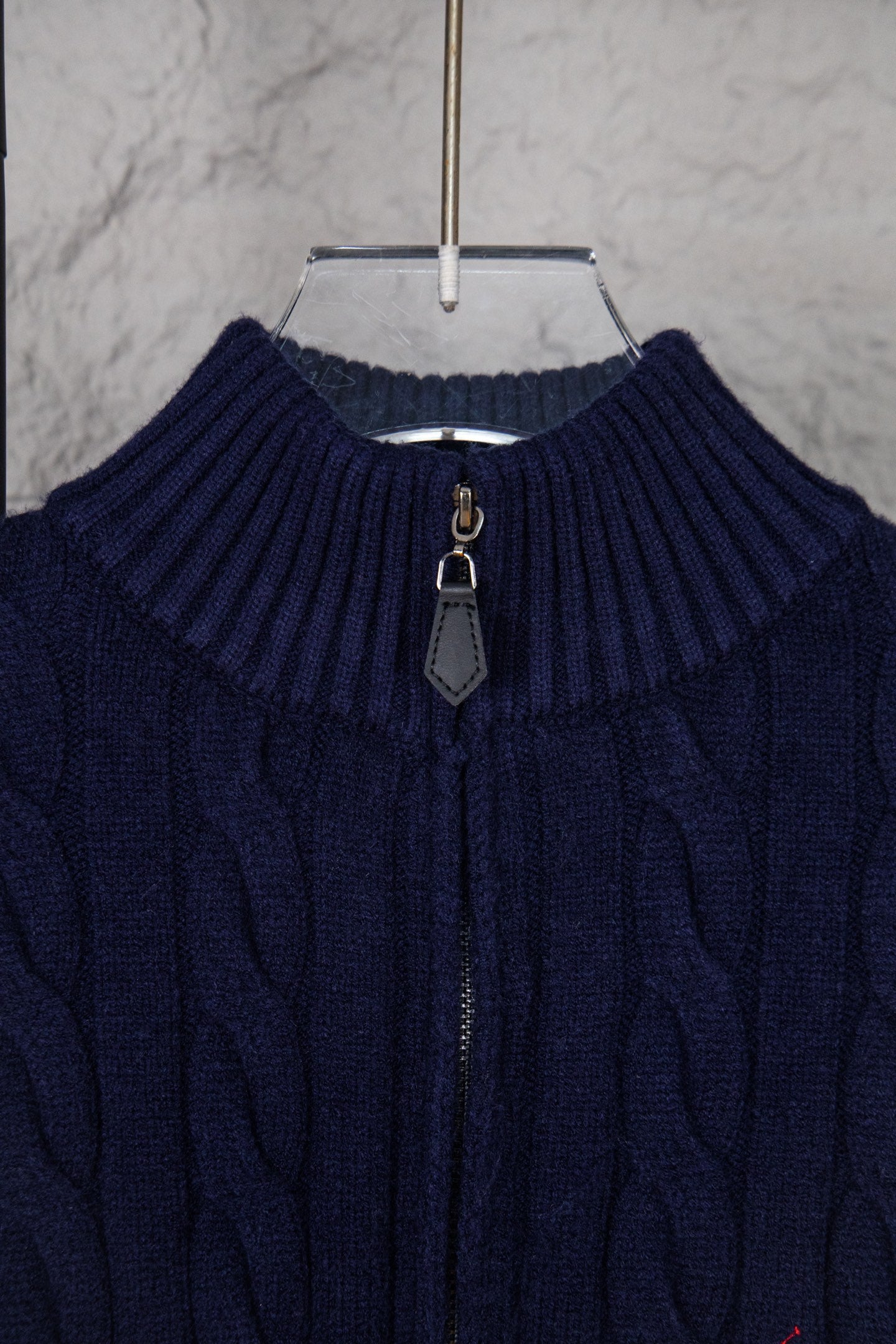 Navy cable-knit quarter-zip sweater neckline with zip pull and ribbed collar