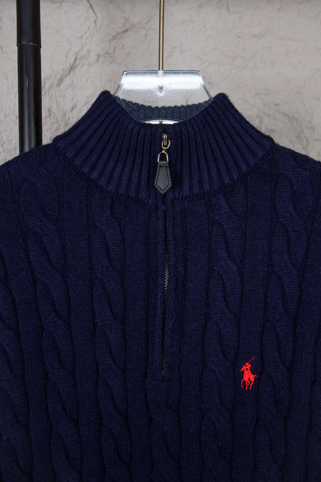 Navy cable-knit quarter-zip sweater collar with zip pull and small red logo
