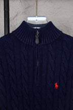 Navy cable-knit quarter-zip sweater collar with zip pull and small red logo