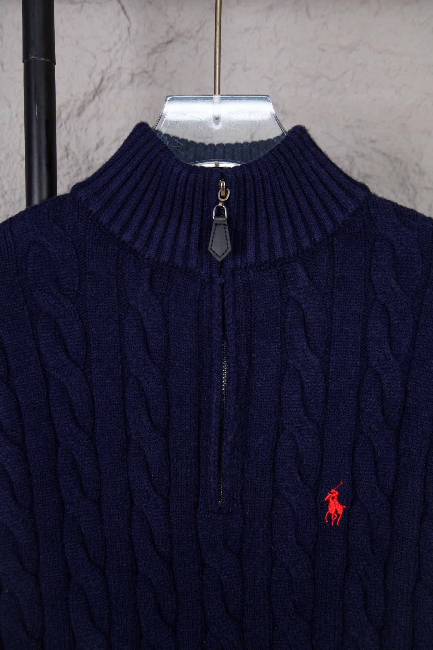 Navy cable-knit quarter-zip sweater collar with zip pull and small red logo