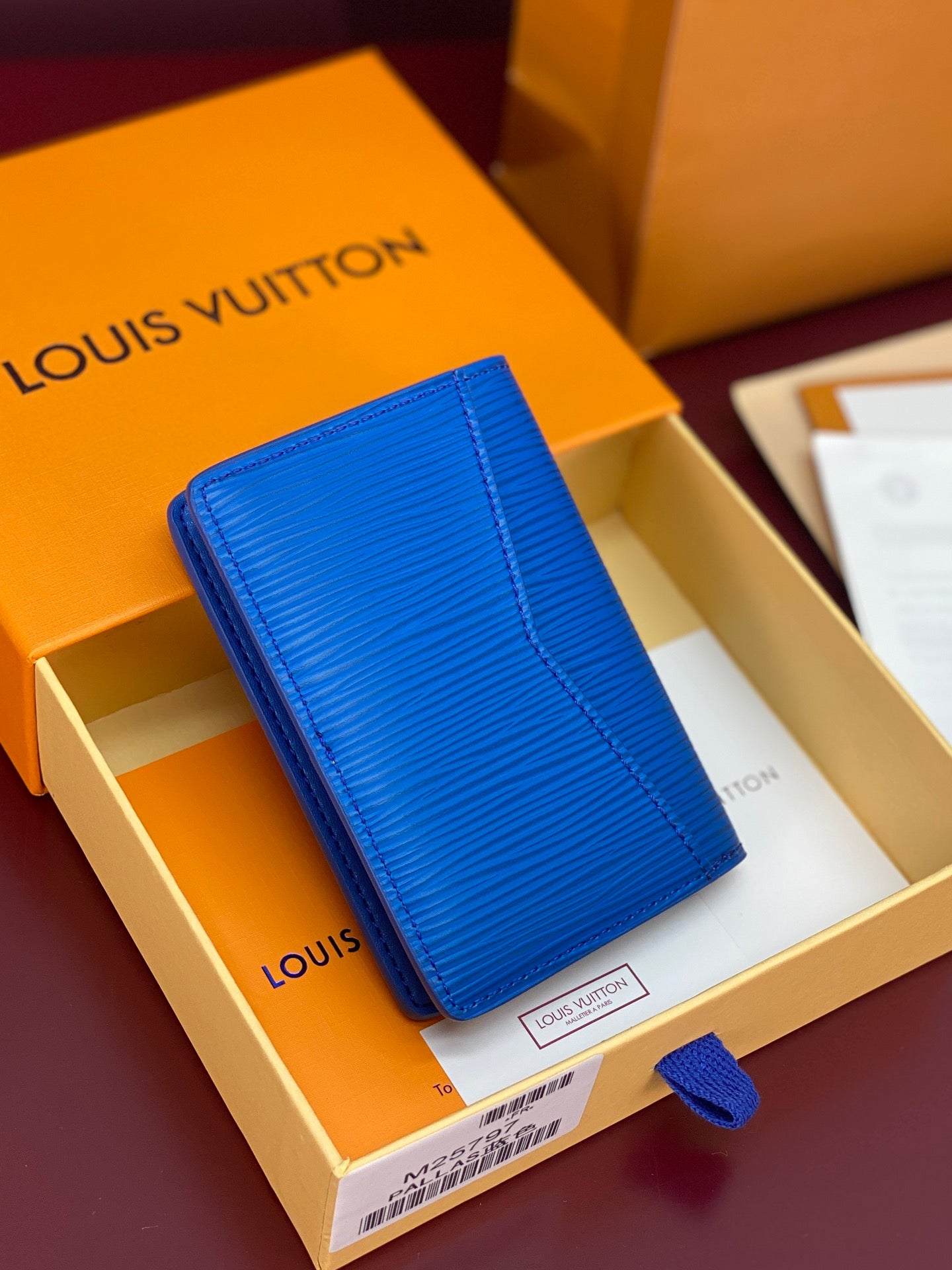 Blue Louis Vuitton card holder with textured pattern and foldover flap, front view.