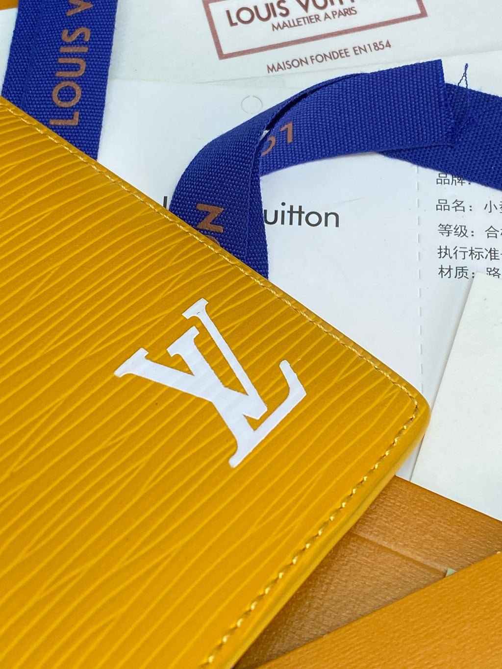 Yellow leather card holder close-up with large LV logo on textured surface