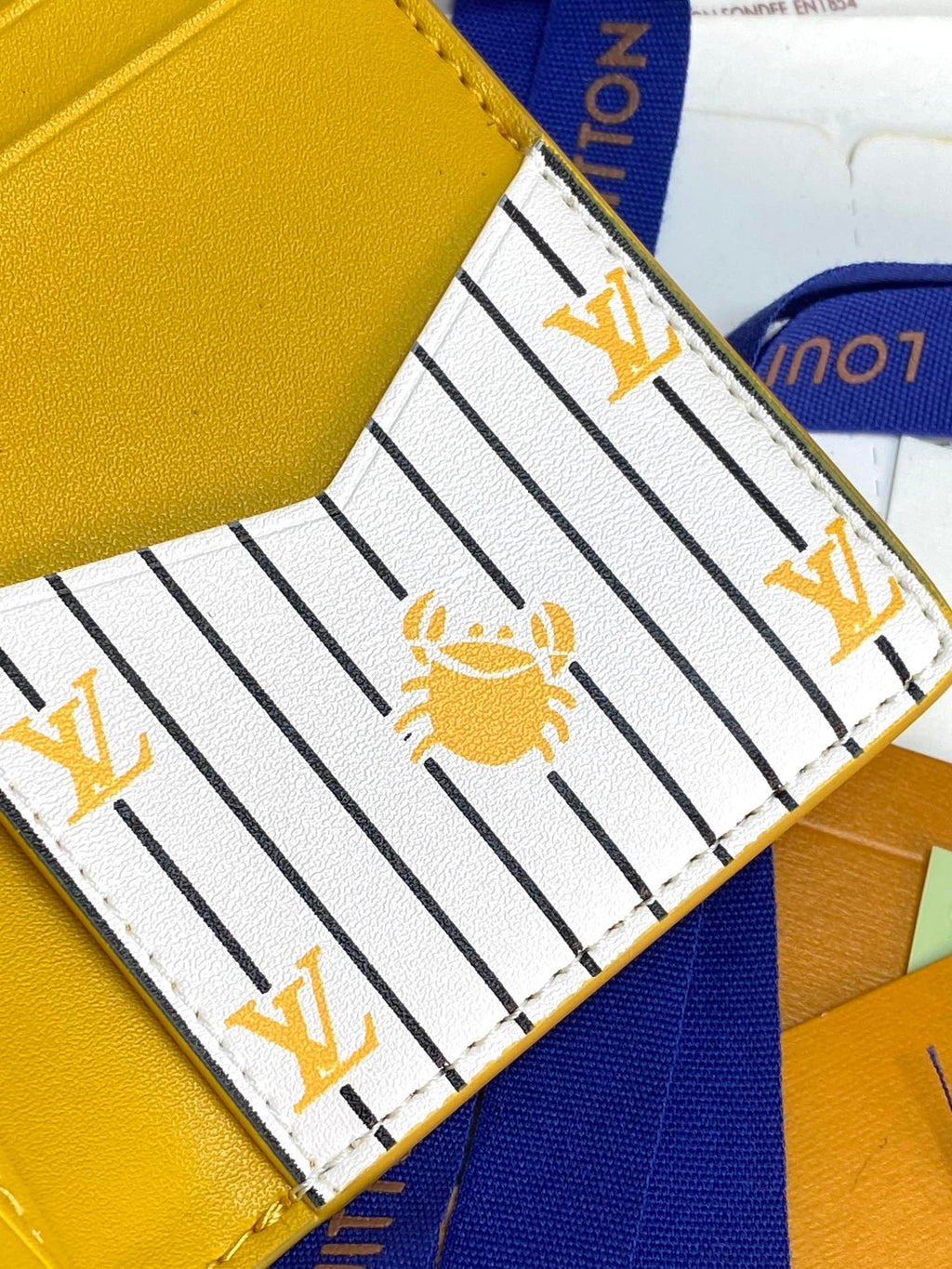 Louis Vuitton card holder interior close-up, striped lining with gold bee motif